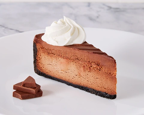 Brasserie Godiva® Double Chocolate Cheesecake slice with whipped cream and chocolate pieces