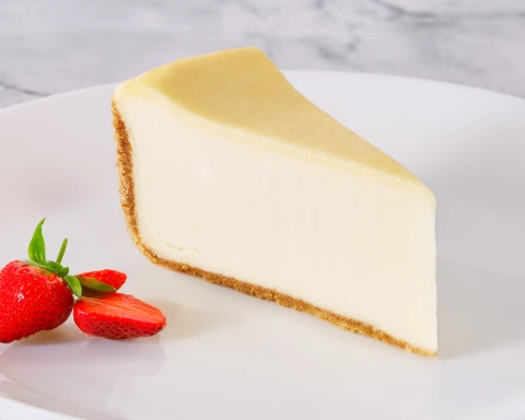 Brasserie Original Cheesecake slice on a white plate with fresh strawberries