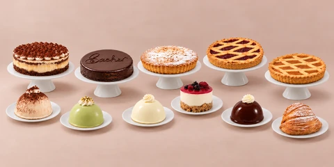 Italian cakes, fruit crostatas and individual desserts on white stands against a peach backdrop