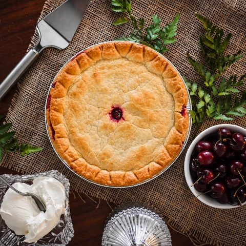 Whole cherry pie photographed from above with cherries