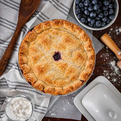 Whole wild blueberry pie photographed from above with blueberries